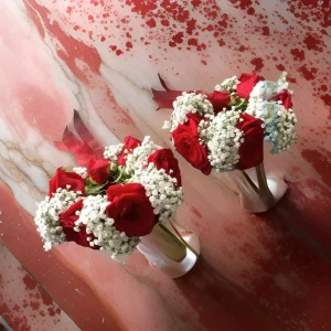 A bridal kangan made of baby's breath and red roses.