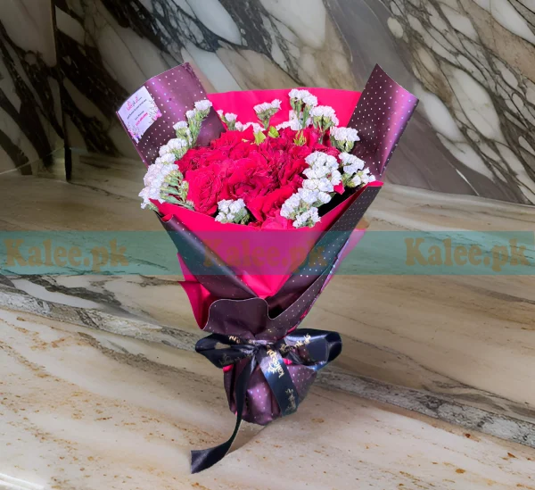 A nicely wrapped bouquet of red roses and statice.