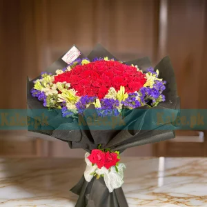 A bouquet of red roses and statice, artfully wrapped.