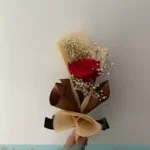 A single red rose accompanied by delicate baby's breath.