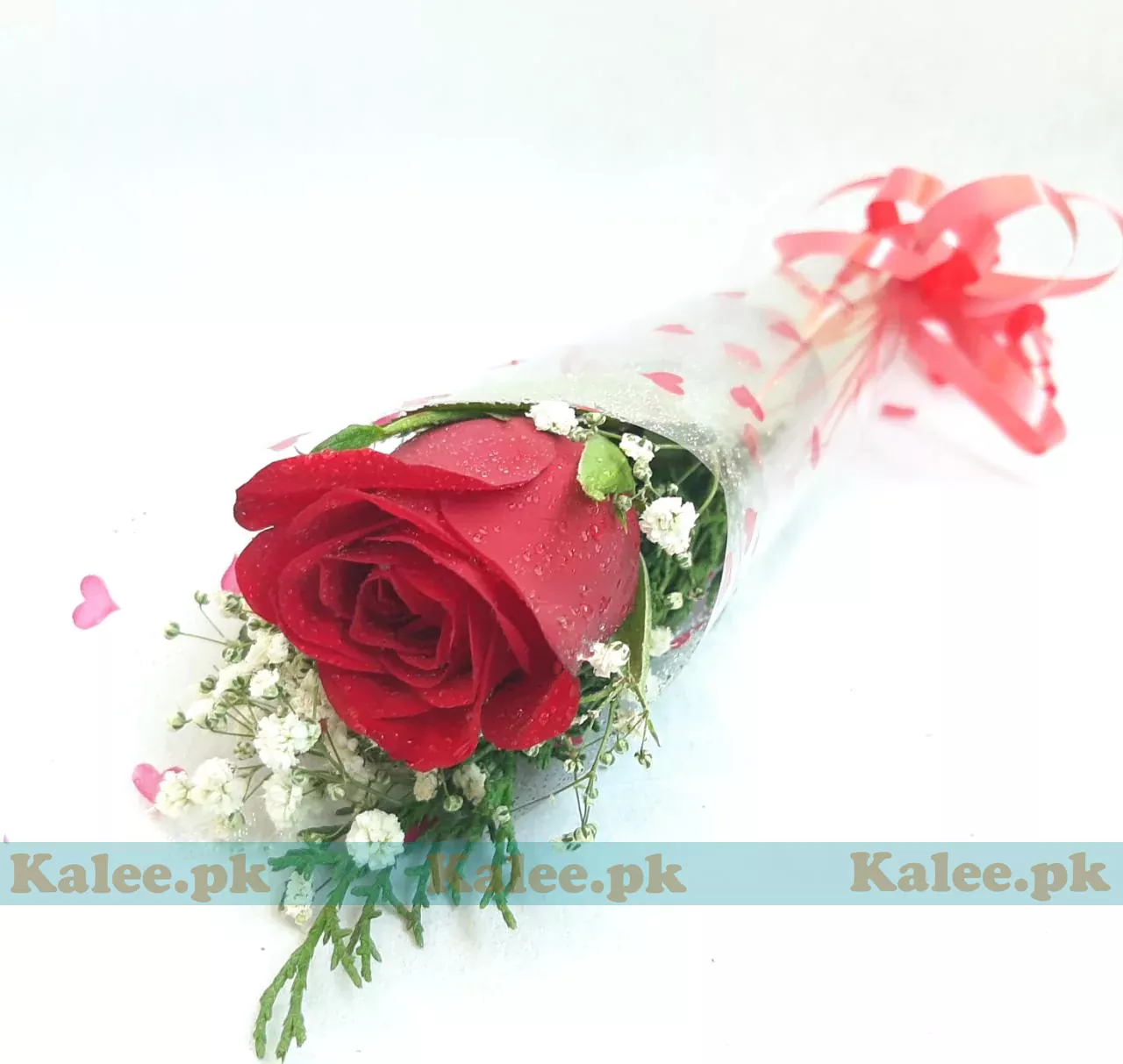 A single red rose adorned with baby's breath and wrapped in clear plastic.