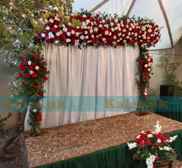 Stage adorned with white daisies, glades, and red roses