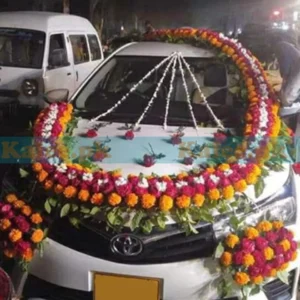 Car adorned with red roses, marigold, and glades decoration.