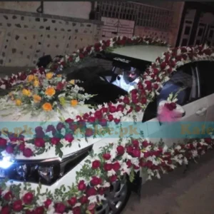 Car adorned with red and yellow roses and white glades decoration.