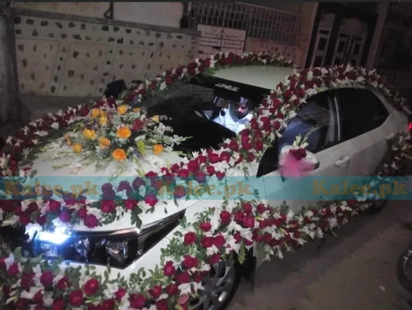 Car adorned with red and yellow roses and white glades decoration.