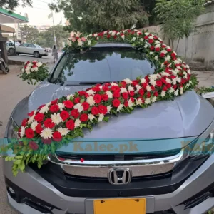 A wedding car adorned with red rose Gul-e-Dawoodi decoration.