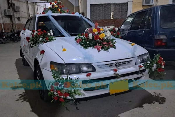 Car adorned with a beautiful decoration featuring roses, glades, and daisy flowers.