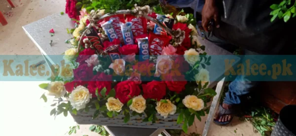 Assorted Chocolates arranged in a Basket with English Red, Yellow, and Pink Roses