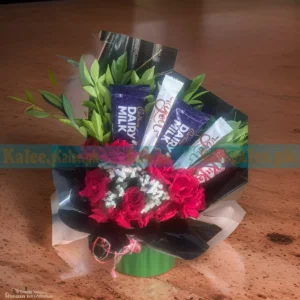 A bouquet featuring statice flowers and English red roses accompanied by chocolates
