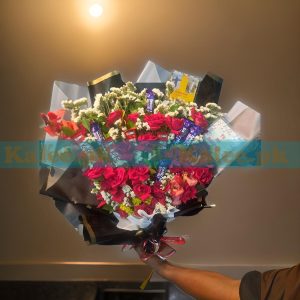 A delightful Chocolates Bouquet with Red Roses, featuring fresh English red roses, statice flowers, 4 KitKat bars, and 5 Dairy Milk chocolates, elegantly arranged for a perfect gift.