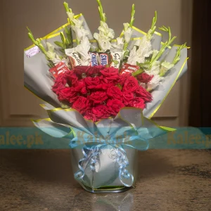 A bouquet featuring chocolates, white glades, and red roses.